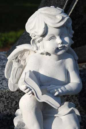 Stauette of a cherub reading a book